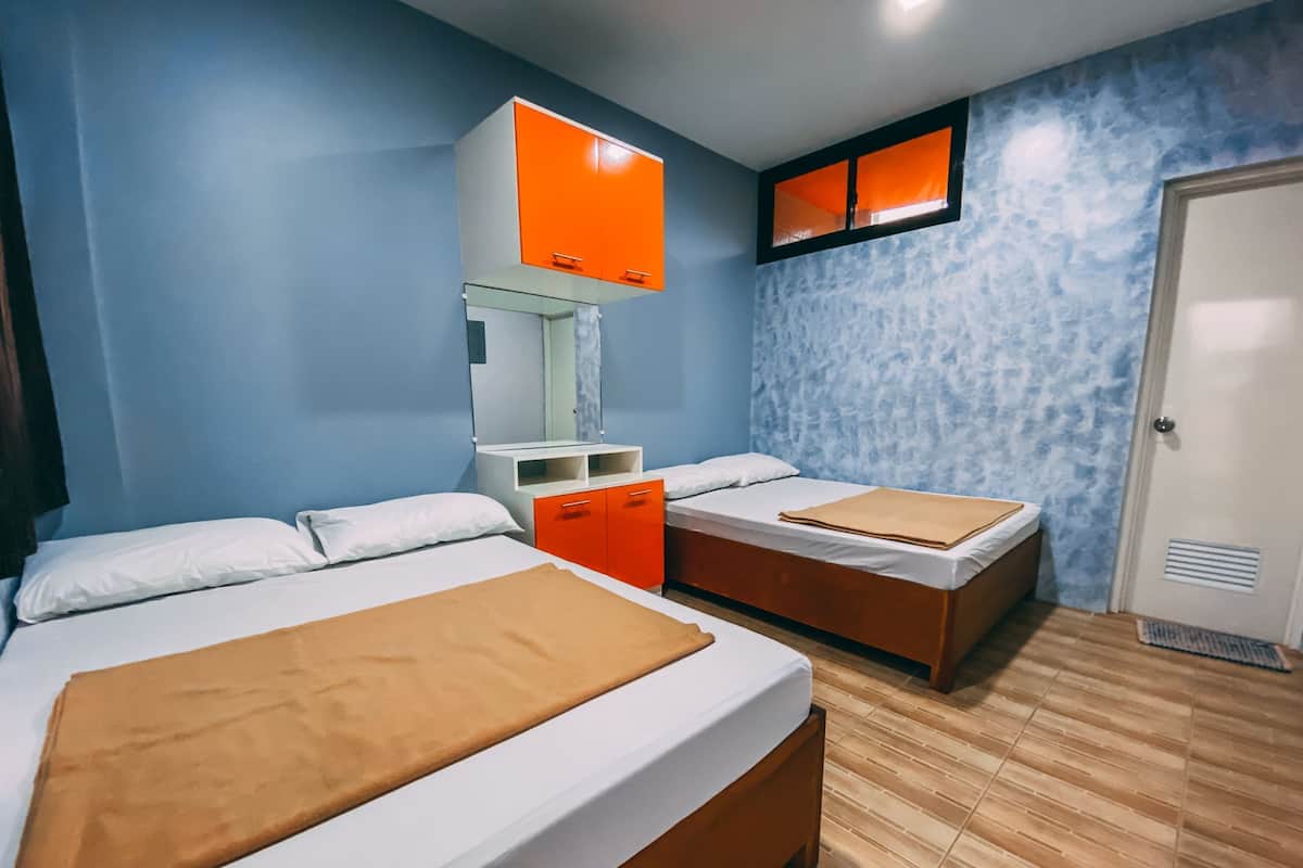 A room with two beds, a mirror, a window, and a door.
