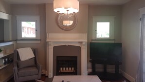 A living room with a fireplace, a piano, a sofa, and a chandelier.