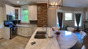 A modern kitchen with white cabinets, a built-in oven, and a large island with a sink.