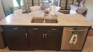 A kitchen with a double sink, dark cabinets, and a built-in dishwasher.