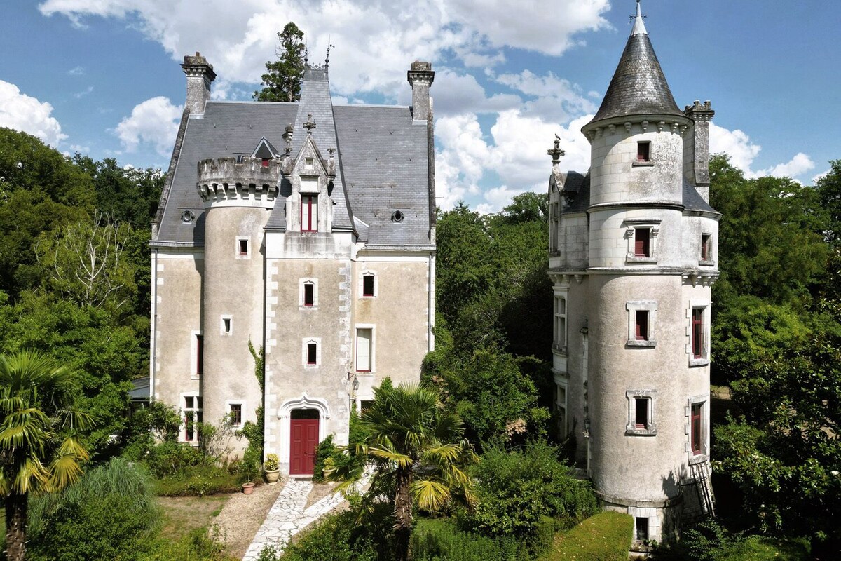 Un castillo grande e histórico, con una imponente torre central y una torre más pequeña a la derecha.