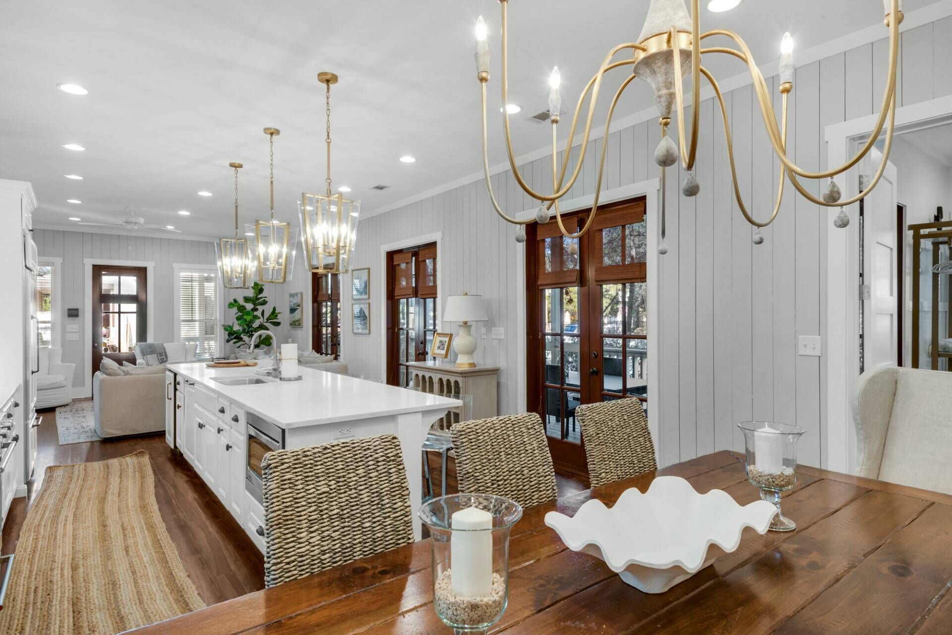A spacious kitchen with a large island, pendant lighting, and a dining area with a wooden table and woven chairs.
