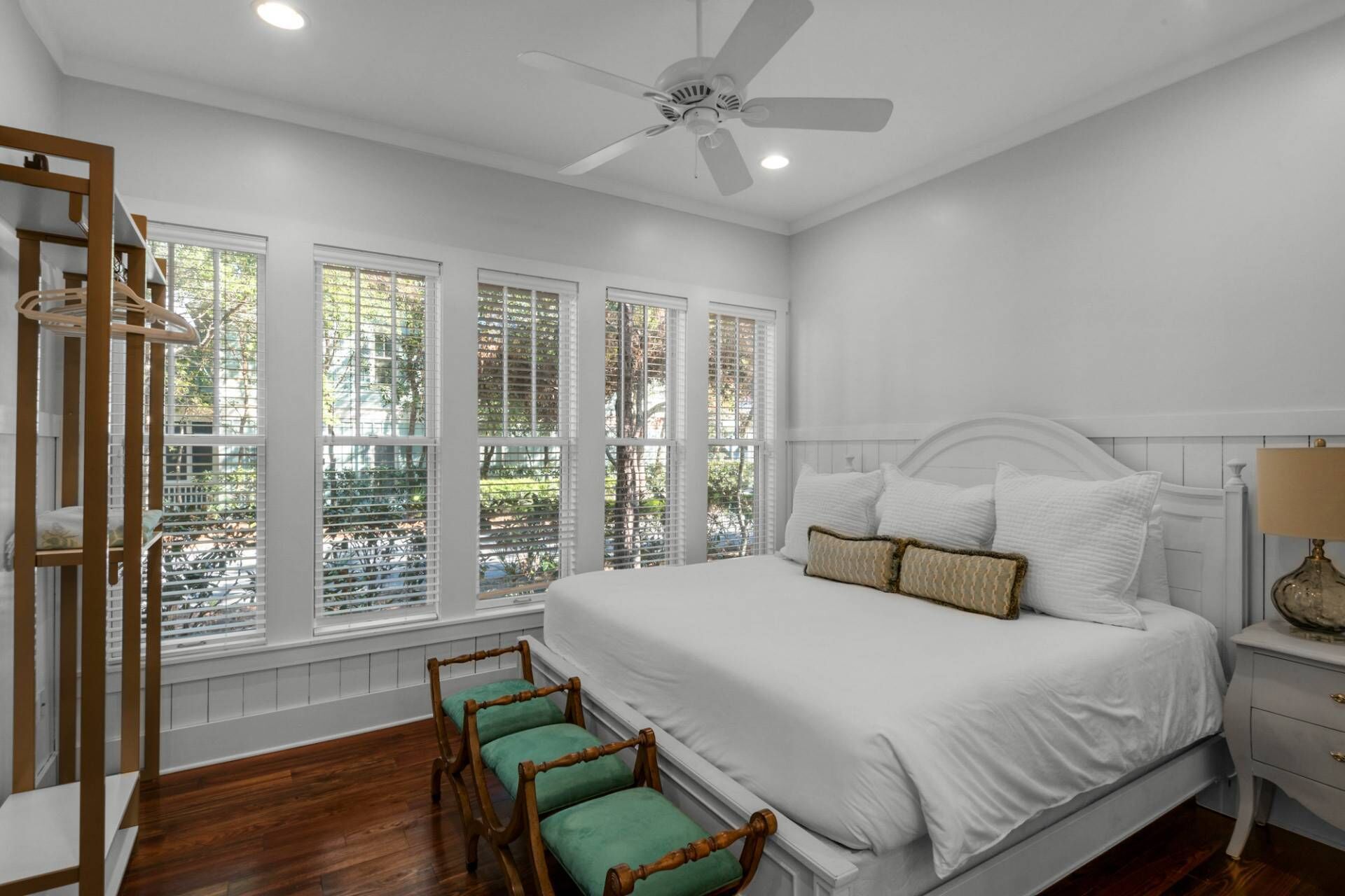 A bedroom with a large bed, a ceiling fan, and a window with blinds.