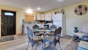 A kitchen with a dining table and chairs, wooden cabinets, a refrigerator, and a clock on the wall. - Fort Worth Home w/ Patio: 5 Mi to Dtwn! (Fort Worth)