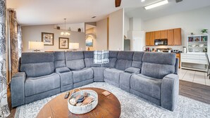 A modern living room with a gray sectional sofa, a wooden coffee table, and a ceiling fan. - 11 Mi to Disney: Family-Friendly Home in Davenport (Davenport)