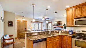 A kitchen with granite countertops, wooden cabinets, stainless steel appliances, and pendant lighting. - Central Fraser Condo 8 Mi to Winter Park Ski! (Fraser)