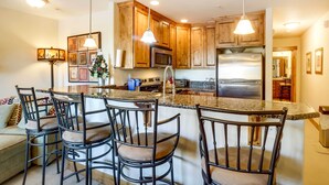 A modern kitchen with wooden cabinets, a stainless steel refrigerator, and a granite countertop. - Central Fraser Condo 8 Mi to Winter Park Ski! (Fraser)
