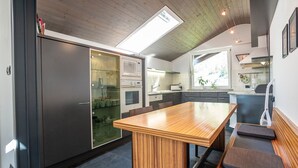 Une cuisine moderne avec une table à manger en bois, des appareils électroménagers intégrés et une lucarne.