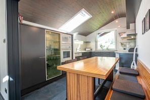 Una cocina moderna con una mesa de comedor de madera, electrodomésticos integrados y un tragaluz.