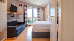 Une chambre d’hôtel moderne équipée d’un lit, d’un canapé, d’une télévision et offrant une vue sur l’extérieur.