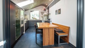 Une cuisine moderne avec une table et des bancs de salle à manger en bois, un four encastré et une fenêtre laissant entrer la lumière naturelle.