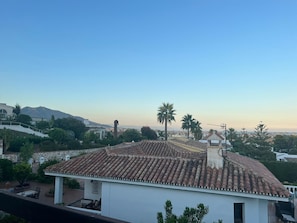 Ein Gebäude mit einem Ziegeldach, einem Glockenturm und Blick auf eine Berglandschaft und Stadtansicht.