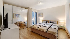 Een slaapkamer met een groot bed, een televisie, een bureau en een raam met gordijnen.