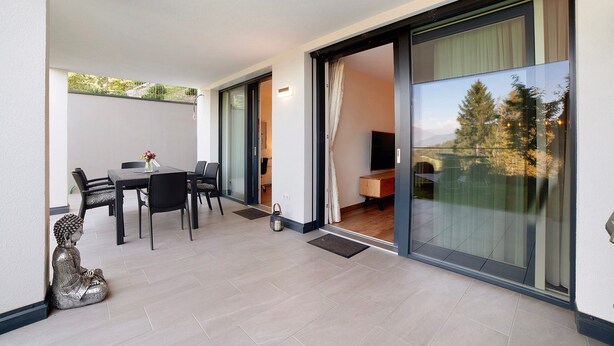 Een modern interieur met een eethoek, een beeld en een glazen schuifdeur naar een balkon.