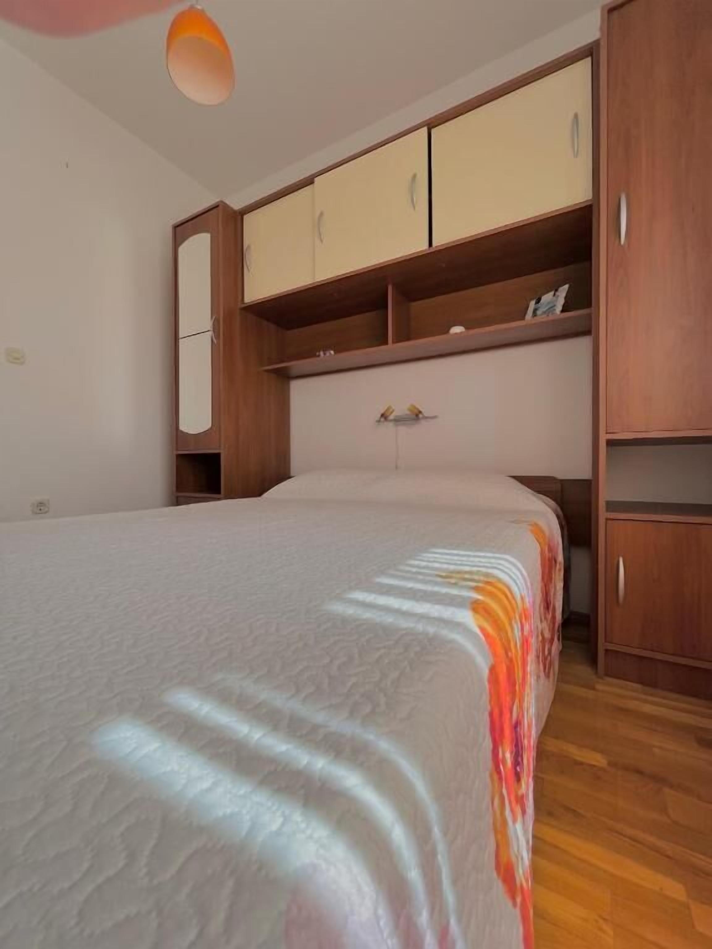 A bedroom with a bed, wooden wardrobe, and a ceiling light.