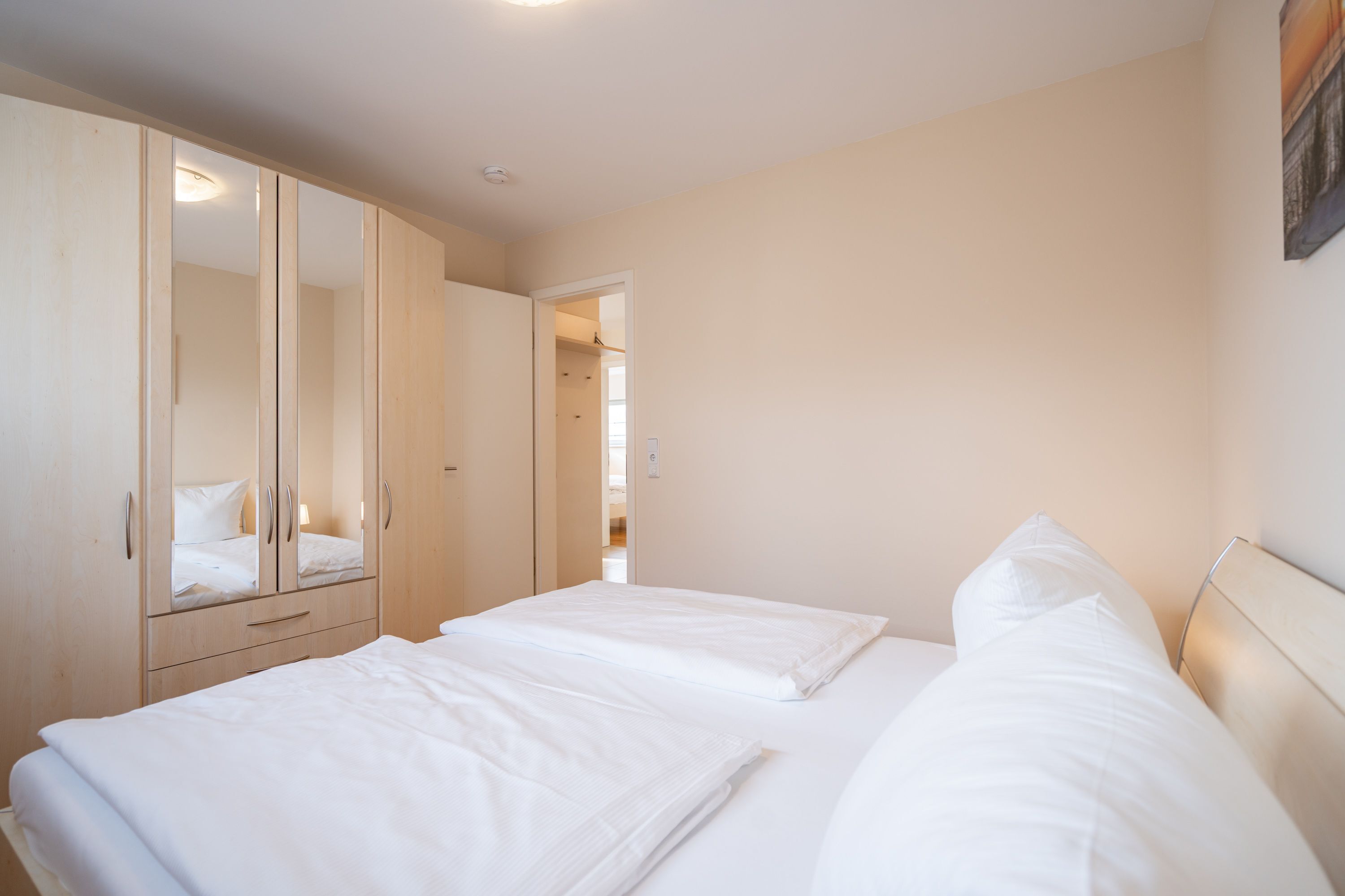 Een slaapkamer met twee bedden, een kledingkast en een deur naar een andere kamer.