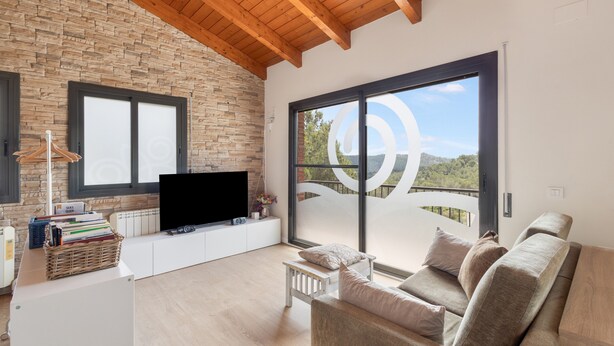 A modern living room with a television, sofa, and large windows. - Studio 'Guest House - Loft Cim Apartments 3' with Mountain Views, Wi-Fi, and Air Conditioning (Olivella)