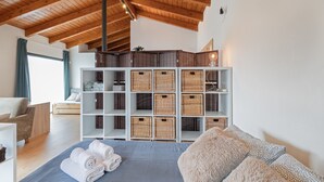 A bedroom with a wooden ceiling, a bed with rolled towels, a sofa, and wicker baskets on shelves. - Studio 'Guest House - Loft Cim Apartments 3' with Mountain Views, Wi-Fi, and Air Conditioning (Olivella)