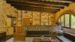 A stone-walled room with a bench, a table with a plant, and shelves with decorative items. - Holiday Home "Mas Renart" with Mountain View, Pool, Wi-Fi, Garden & Terrace (Mollet de peralada)