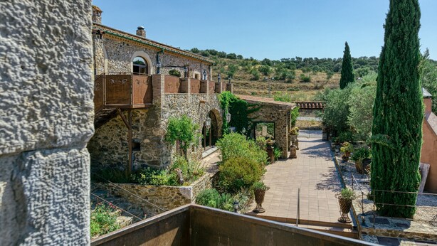 A courtyard with stone walls, potted plants, and a pathway leading to a building with a tiled roof. - Holiday Home "Mas Renart" with Mountain View, Pool, Wi-Fi, Garden & Terrace (Mollet de peralada)