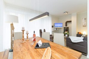 A modern hotel room with a wooden dining table, a sofa, and a TV. - Villa Limora, App. 03 (Heringsdorf)