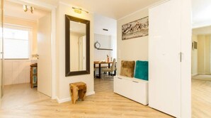 Ein modernes Interieur mit Holzboden, einem weißen Kleiderschrank, einem Spiegel und einer Essecke mit einer Uhr.