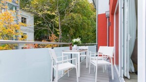 Ein Balkon mit weißen Stühlen und einem Tisch, umgeben von Glasgeländern.