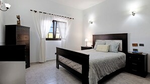 A bedroom with a bed, nightstands, a dresser, and a window with curtains. - Peaceful Villa near Famara – Ideal for Families & Groups, Up to 9 Guests (House + Studio) (Soo)
