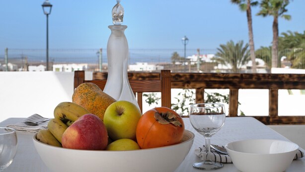 A table with a fruit bowl, a wine glass, and a candle. - Peaceful Villa near Famara – Ideal for Families & Groups, Up to 9 Guests (House + Studio) (Soo)