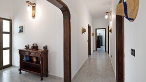 A hallway with a wooden console table, wall-mounted hats, and a light fixture. - Peaceful Villa near Famara – Ideal for Families & Groups, Up to 9 Guests (House + Studio) (Soo)