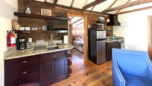 A compact kitchen with wooden beams, a refrigerator, microwave, and a sink.