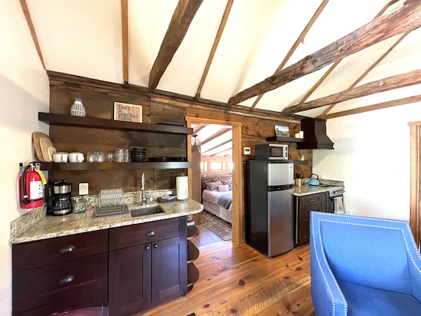Eine kleine Küche mit Holzbalken, einem Kühlschrank, einer Mikrowelle und einem Spülbecken.