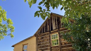 A rustic wooden building with a stone foundation, a wooden upper section, and a window with a grid pattern.