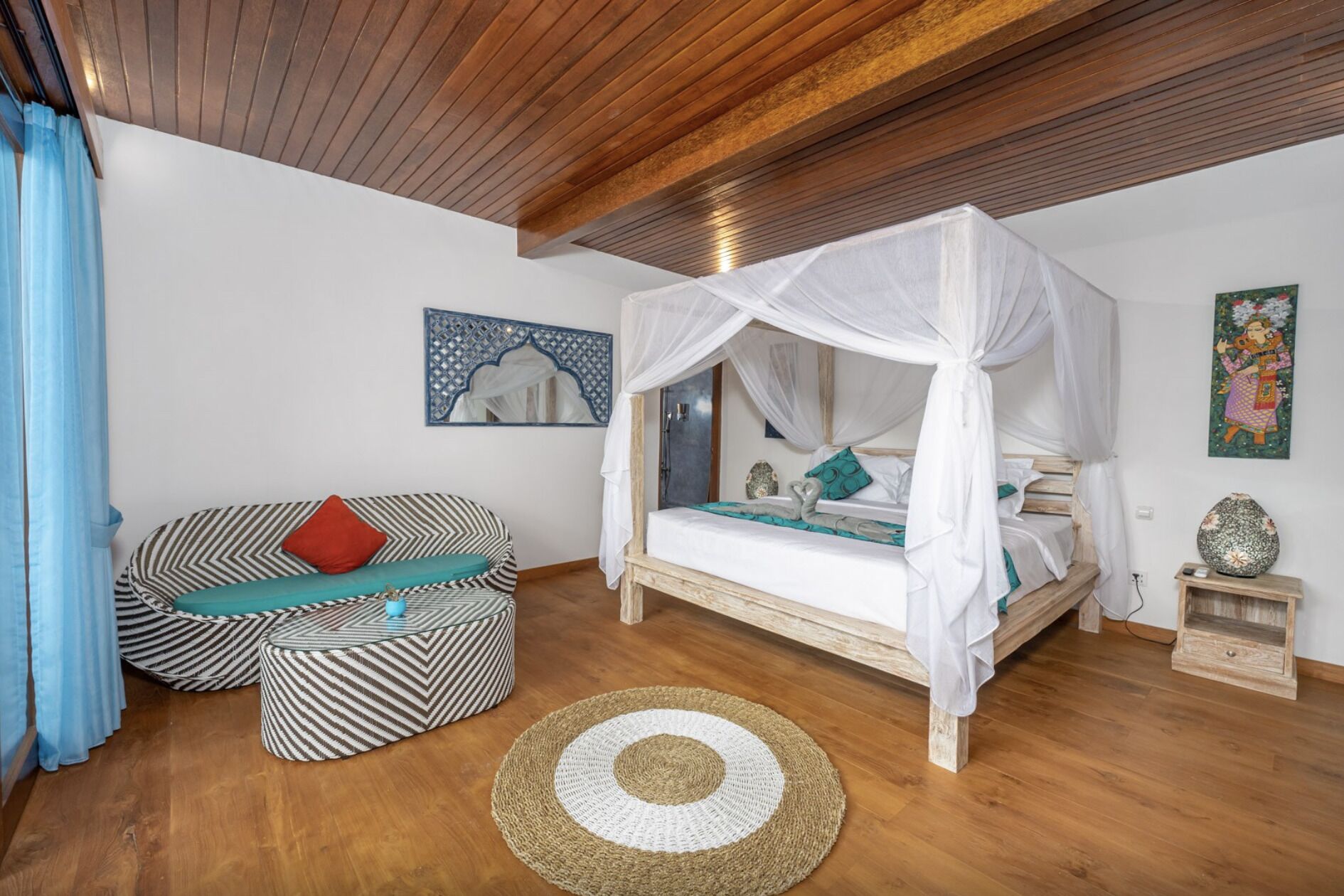 A bedroom with a canopy bed, a striped sofa, a woven rug, and a decorative mirror.