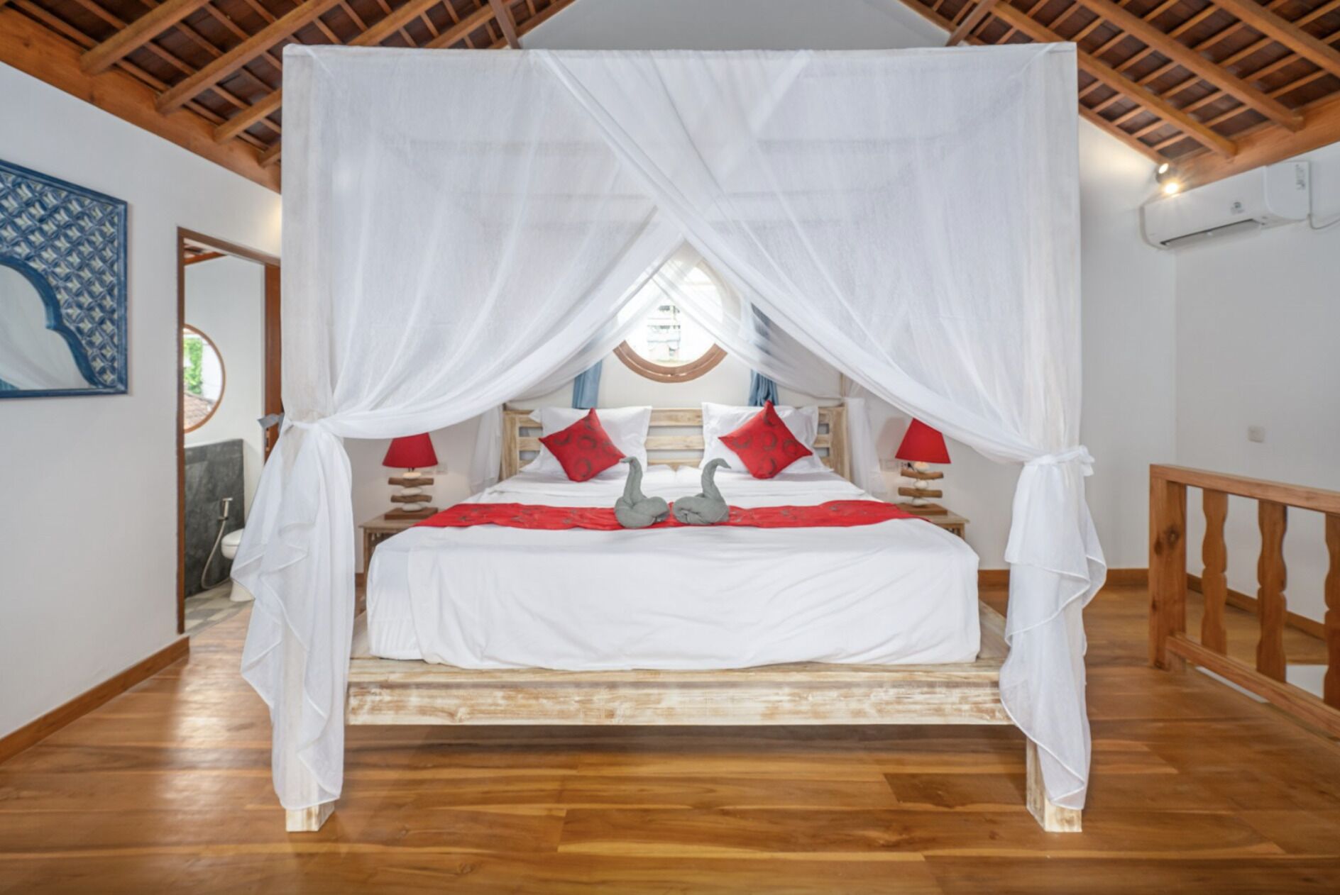 Ein Schlafzimmer mit Baldachinbett, Holzboden und Blick ins Freie durch ein Fenster.