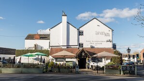 Een wit gebouw met een bord waarop staat: Littleton Arms Hotel Accommodation Free House.