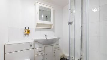 Un bany amb un lavabo blanc, un mirall i una dutxa.