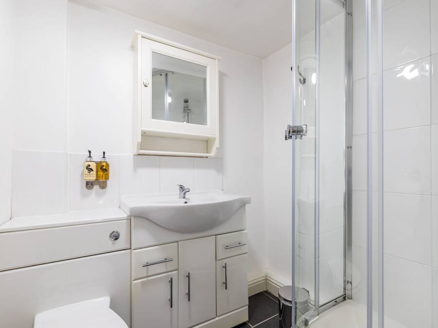 Un bany amb un lavabo blanc, un mirall i una dutxa.