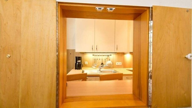 Una cucina compatta con mobili in legno, un lavello e un piano di lavoro.