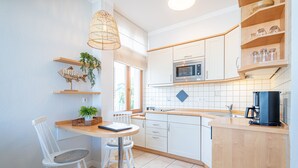 Een moderne keuken met witte kastjes, een houten aanrecht, een magnetron en een koffiezetapparaat.