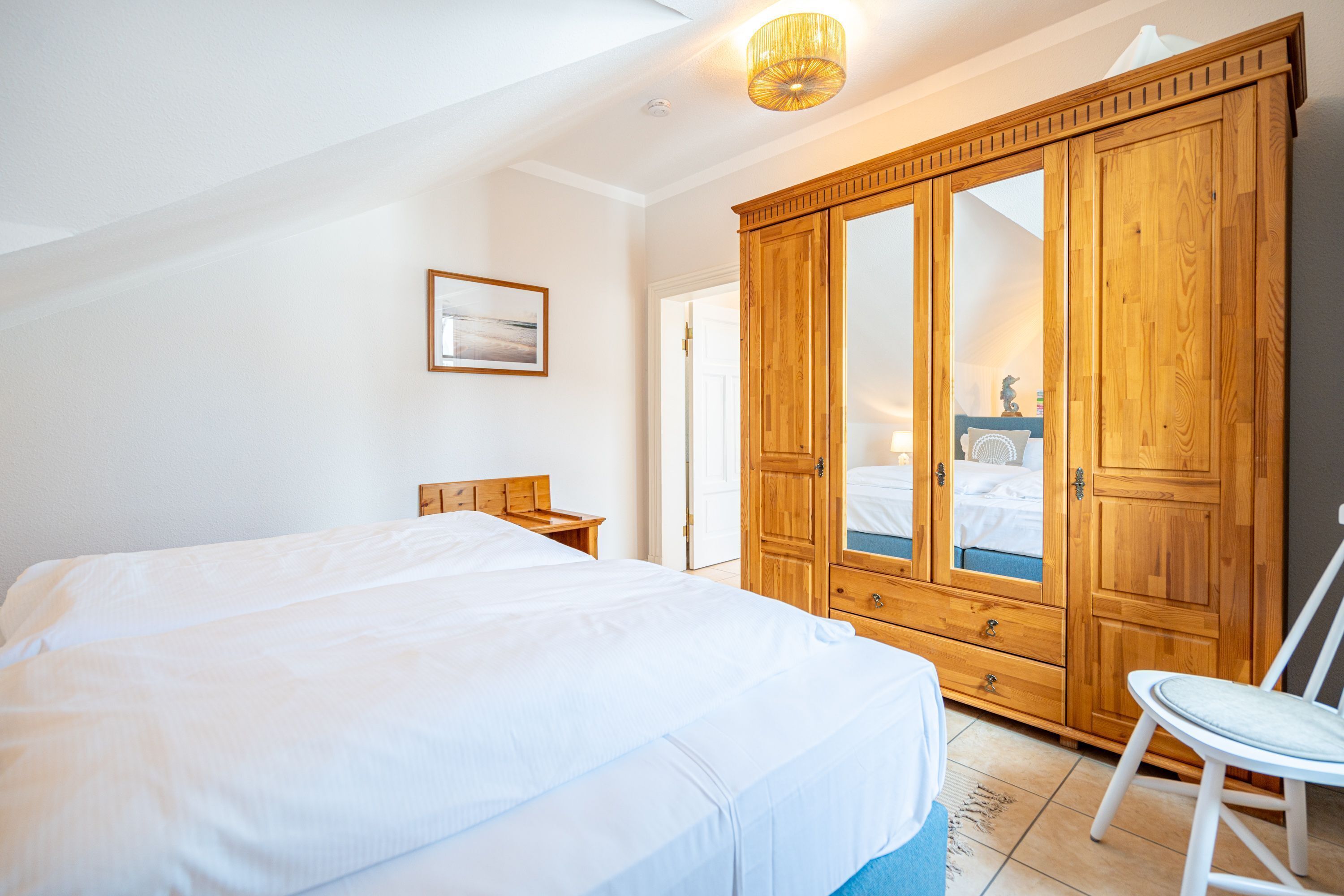 Une chambre avec un grand lit, une armoire en bois et une chaise.