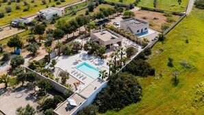 Vue aérienne d’une propriété comprenant une piscine, plusieurs bâtiments et un espace vert environnant.