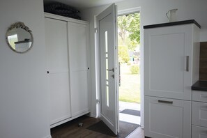 A white interior with a door leading outside, a small rug, and a mirror on the wall. - Cathrins Boddenblick - Cathrin`s Boddenblick (Wustrow)
