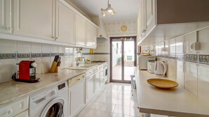 A kitchen with white cabinets, a washing machine, a red appliance, and a tiled backsplash. - Apartment 'Beira Mar' with Sea View, Terrace & Wi-Fi (Armação de Pêra)