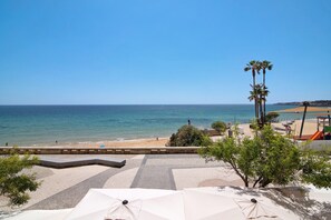 A beach view with umbrellas, palm trees, and a clear sky. - Apartment 'Beira Mar' with Sea View, Terrace & Wi-Fi (Armação de Pêra)