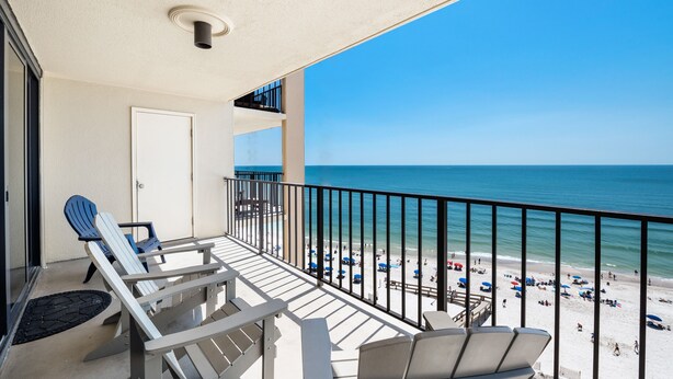 Ein Balkon mit Blick auf den Strand, eine Tür und zwei Adirondack-Stühle.
