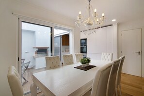 Un coin repas avec une table blanche, des chaises et un lustre.