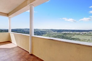 Un balcón con vistas a un paisaje montañoso y un pueblo lejano.