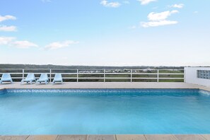 Una piscina con vistas a un paisaje y una valla blanca.