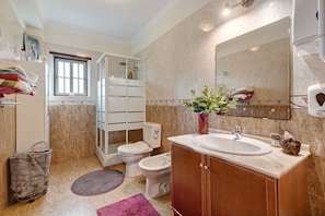 Un baño con ducha, inodoro, lavabo y un espejo grande.